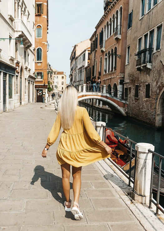 Menina por canal e ponte em Veneza